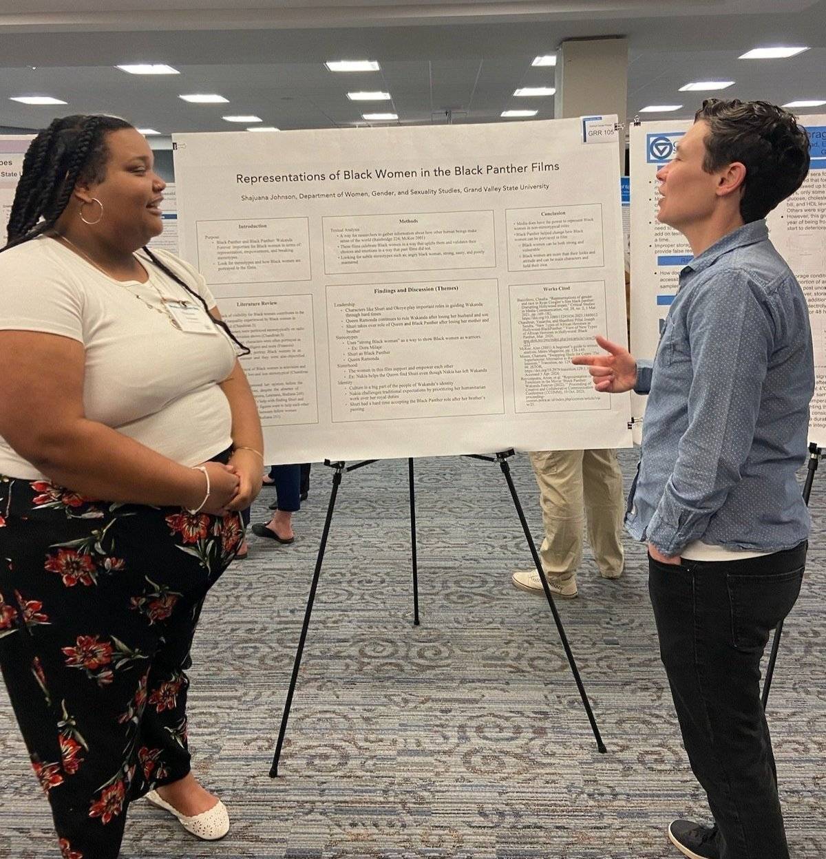 photo of a student presenting a poster project to a professor